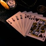 A dimly lit close-up of playing cards with a pocket watch, showcasing a nostalgic casino vibe.