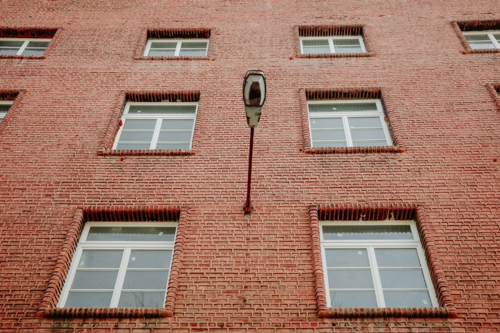 Brick building facade with windows and a lamp.
