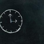 Chalk-drawn clock on a blackboard, symbolizing time and education concepts.